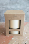 A kraft paper box with a clear window showing a cream-colored plant pot inside, labeled 'HOFF' on the front, set on a terrazzo surface against a textured gray background.
