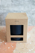A kraft paper box with a clear window displaying a dark blue plant pot, labeled 'HOFF', set on a terrazzo surface against a textured gray background.